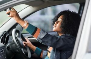 Driver adjusting rear view mirror while behind the wheel of new vehicle 