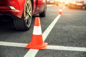 Close-up shot of a car on a lined asphalt lot with parking cones