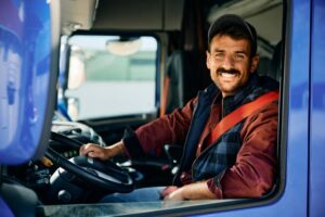 Smiling truck driver in blue commercial truck